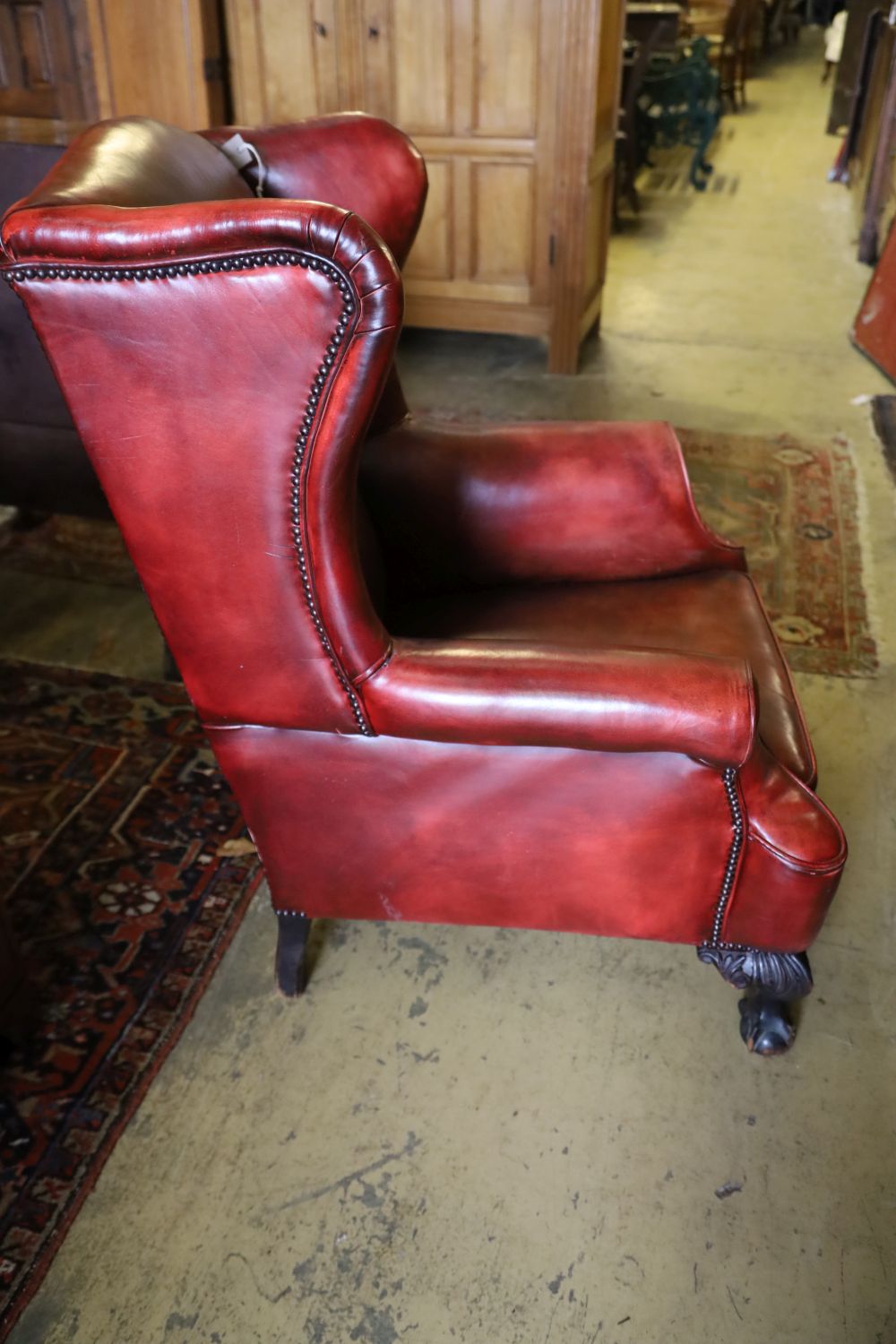 An early 20th century wing back armchair upholstered in burgundy leather on carved claw and ball feet, width 80cm, depth 82cm, height 1